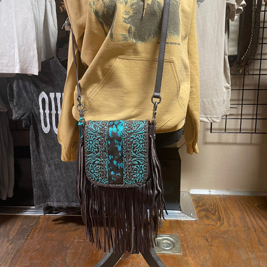 Dark Brown crossbody purse with turquoise floral embossing, blue and black acid wash cowhide in the center, silver studs and dark brown fringe