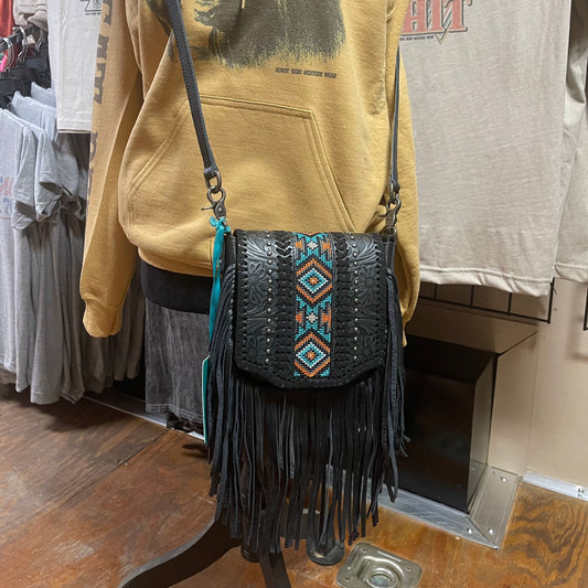 Black crossbody purse with leather fringe, tooled leather, metal studs, and whipstitch detailing