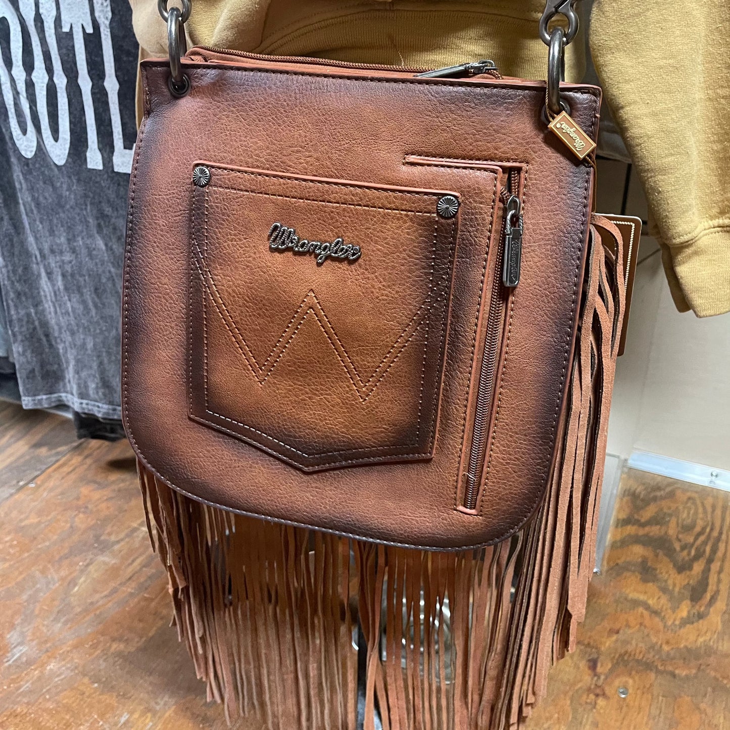 Back view of the brown rivet detailed crossbody bag showcasing the wrangler pocket and the zipper closure concealed carry compartment